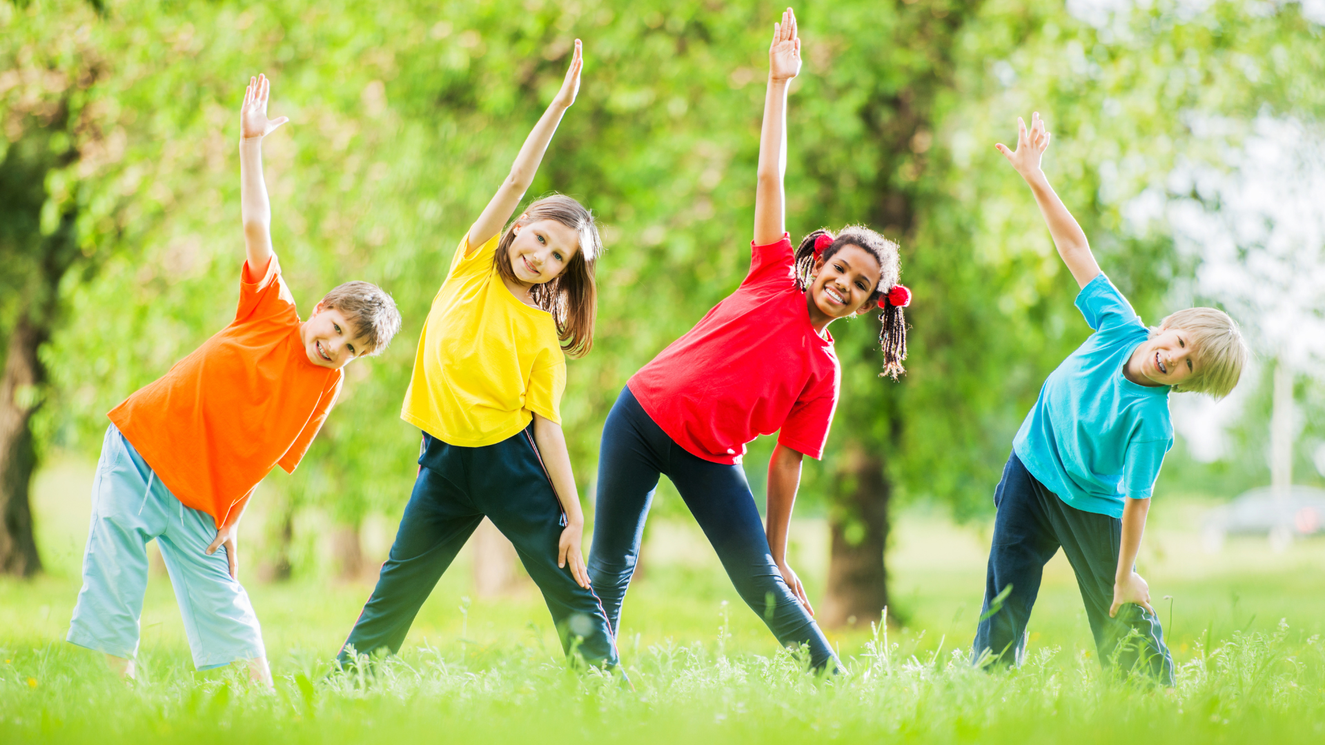 Diverse group of children doing fun outdoor stretching exercises in colorful shirts