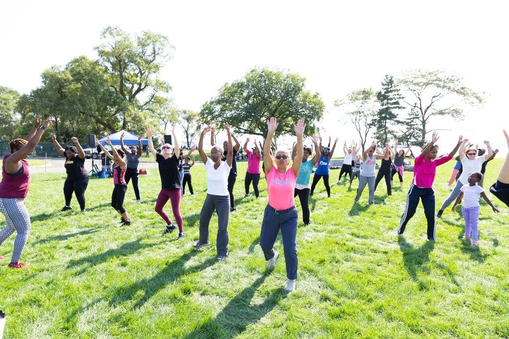 Outdoor group fitness class with people of all ages exercising together in the park
