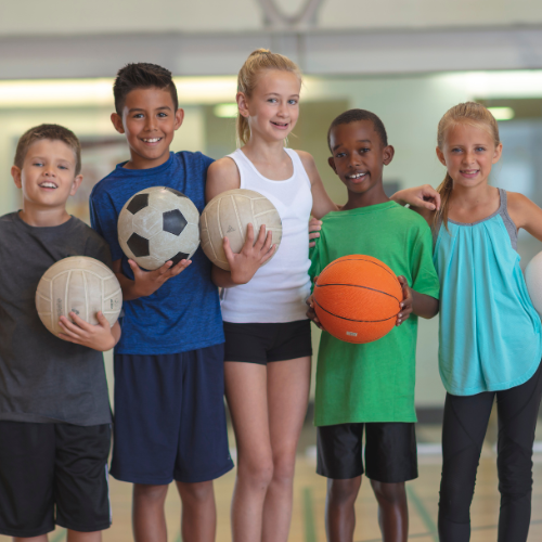 Diverse group of children with sports equipment including soccer, volleyball, and basketball