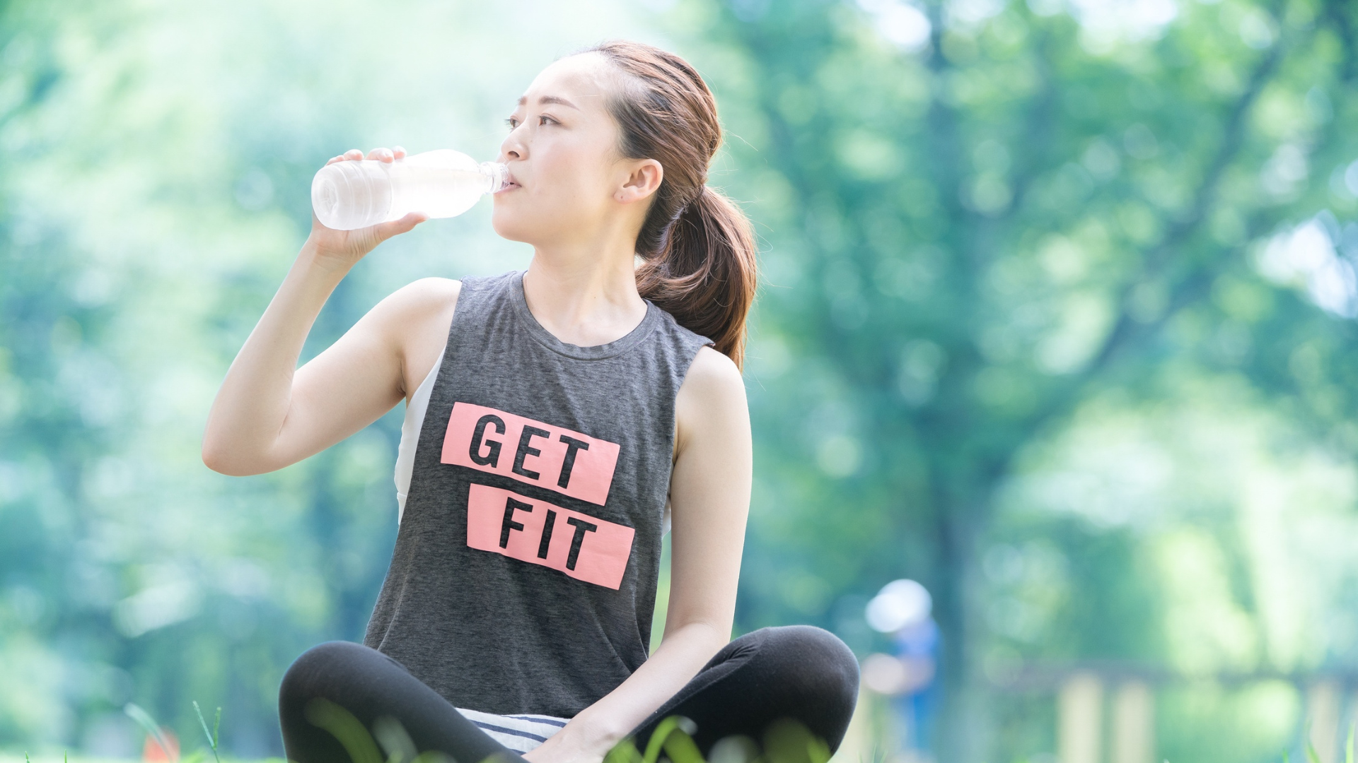 Woman in GET FIT wellness apparel drinking water outdoors